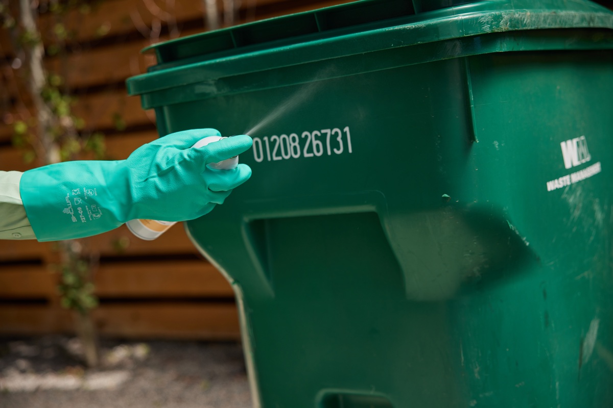 Pest Control Service Treating Garbage Can Service pro treating customer's garbage can