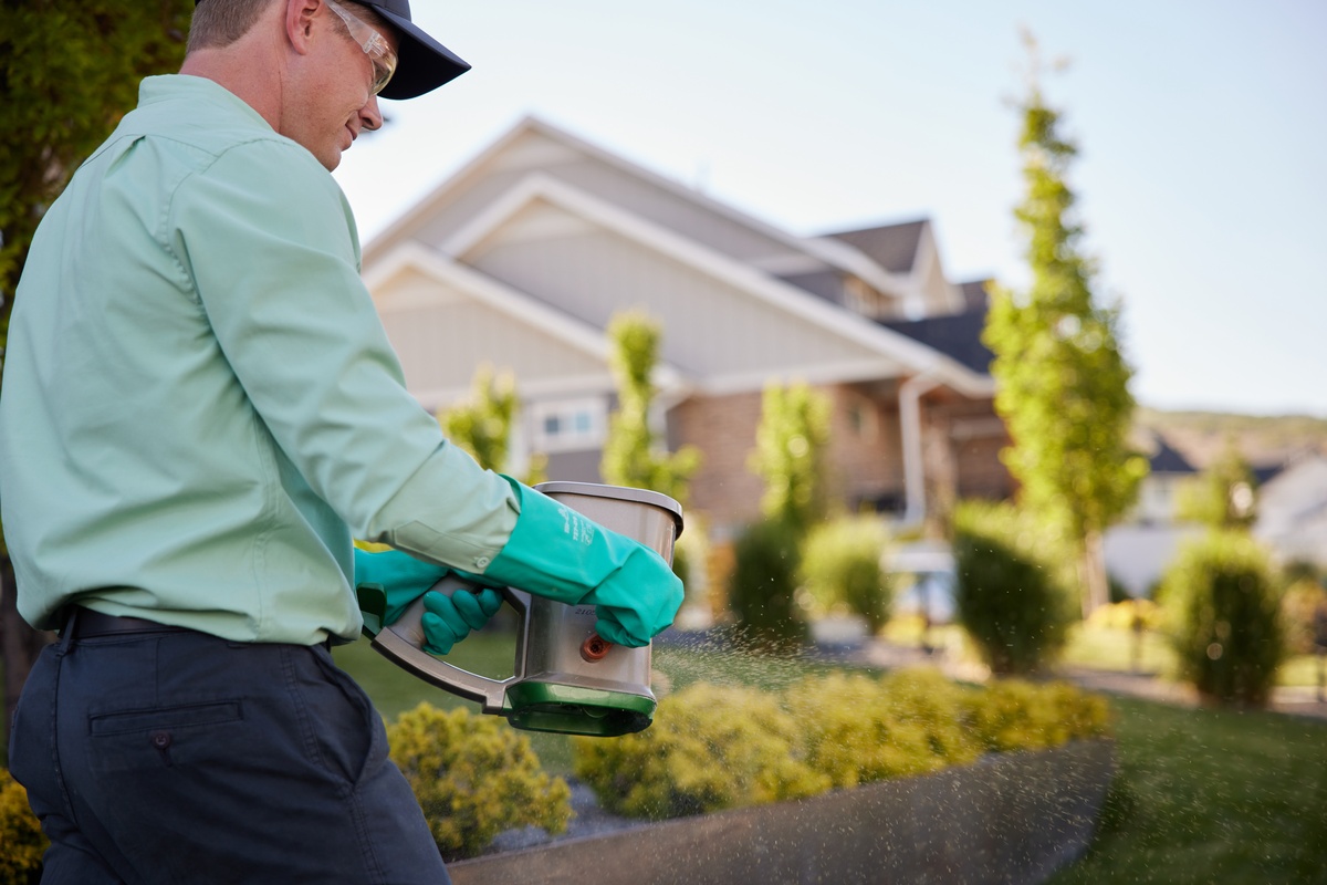 Service pro applying treatment for pests in customer's yard
